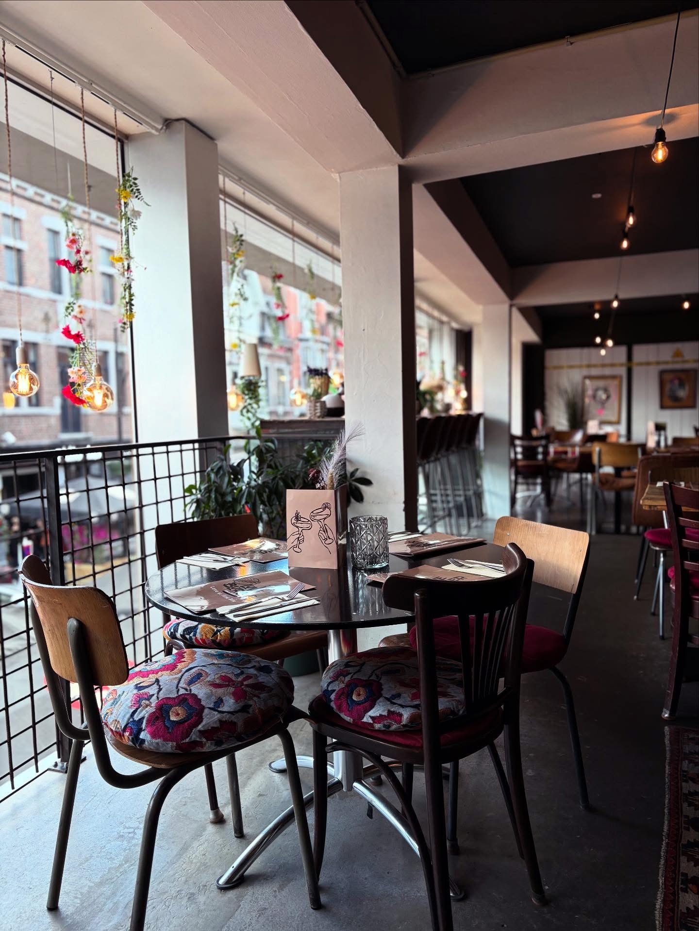 Tables à l'étage avec vue sur la rue, fleurs suspendues et ampoules
